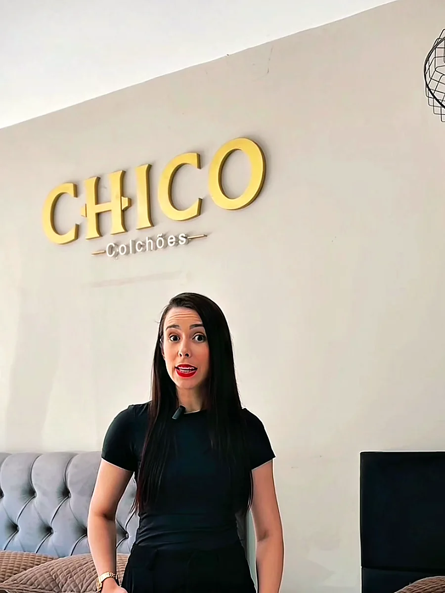 Consultora em frente ao letreiro Chico Colchões