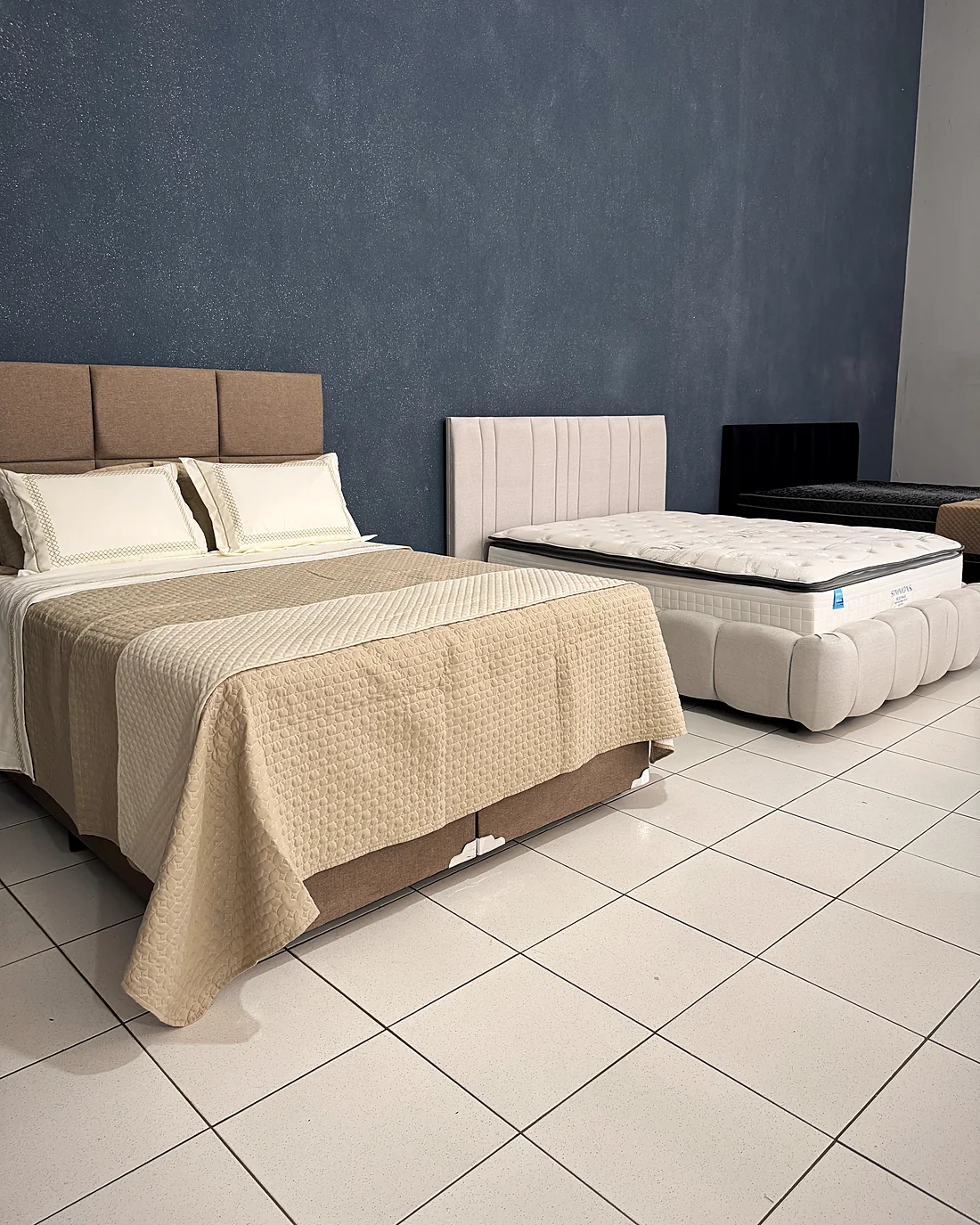 Camas com cabeceiras estofadas e enxovais montadas no showroom da House
